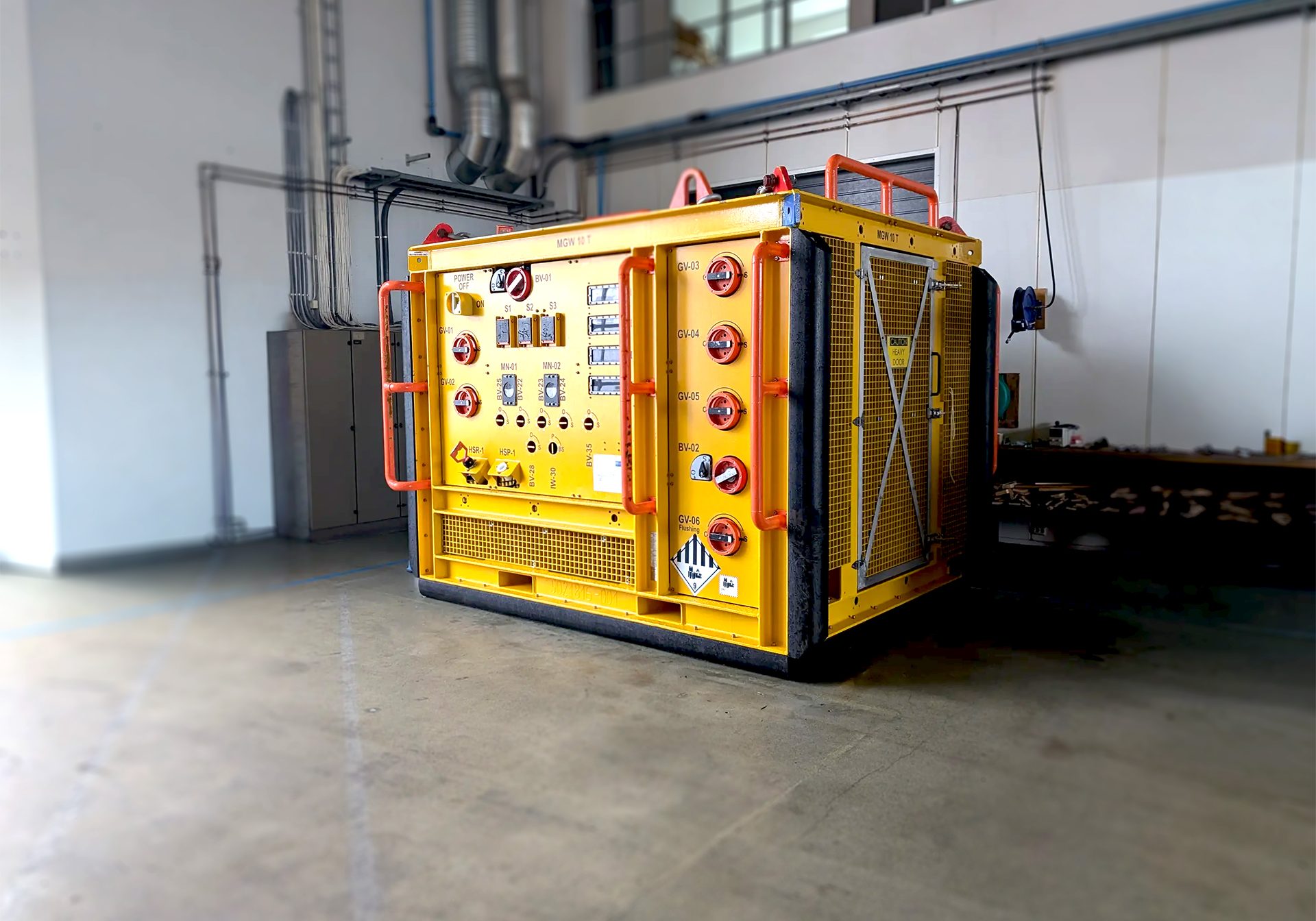 Yellow container rig, -Fluid sampling skid ready for inspection placed in a storage hall.